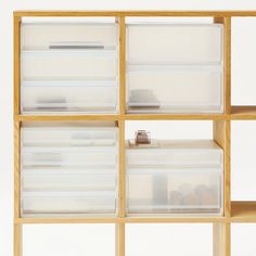 a wooden shelf filled with plastic containers and drawers on top of each other in front of a white wall