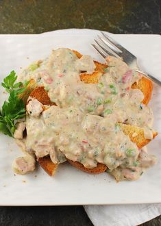 a white plate topped with bread covered in gravy and garnished with parsley