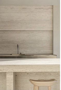 a kitchen counter with two stools next to it and a sink in the background