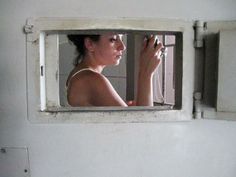 a woman is looking out the window of a ship's bathroom mirror while brushing her hair