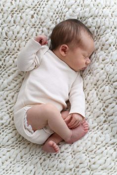 a baby laying on top of a white blanket