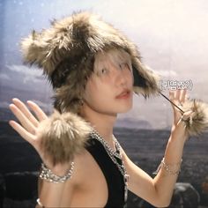 a woman wearing a fur hat and holding her hands out to the side with one hand