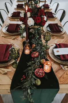 the table is set with candles, plates and red napkins on top of it