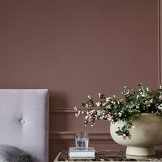 a vase with flowers sitting on top of a table next to a bed and nightstand