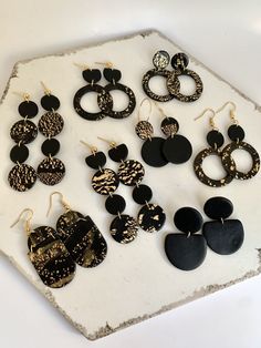 several pairs of earrings sitting on top of a marble slab with black and white designs