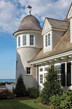 a white house with a gray roof next to the ocean