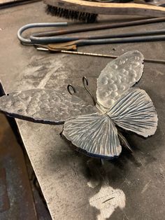 a metal butterfly sitting on top of a table next to some scissors and other tools