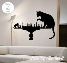 a cat sitting on top of a chess board wall decal in a living room