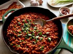 a pot filled with beans and vegetables on top of a table next to other dishes