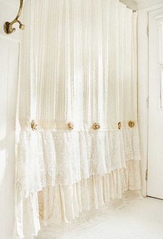 there is a curtain in the corner of this bathroom with lace on it and gold hardware