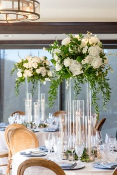 there are many tall vases with flowers on top of the tables at this wedding reception