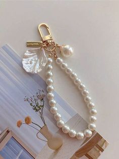 a white pearl necklace with a gold keychain attached to the end of it