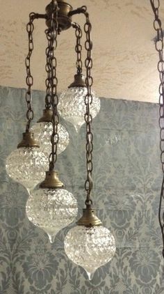 three lights hanging from a chandelier in a room with damask wallpaper