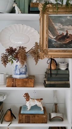 there is a white shelf with books and vases on it, along with other items