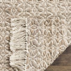 an area rug with fringes on the floor and wood floors in front of it