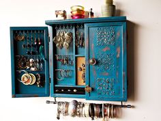 a blue cabinet with jewelry hanging from it's sides