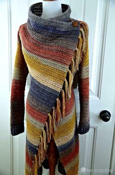 a multicolored sweater with fringes is on display in front of a door