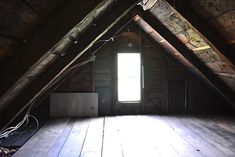 an attic with wooden floors and exposed walls, looking into the light coming through the window