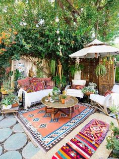 an outdoor living area with couches, tables and umbrellas in the middle of it