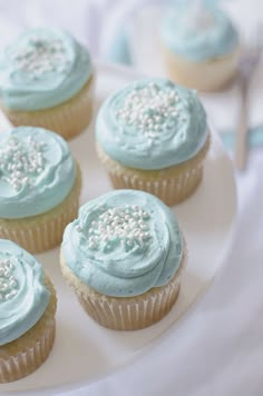 cupcakes with blue frosting and sprinkles on a plate