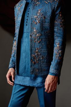 New Teal Short Jacket | Jatin Malik Introducing our latest creation: the teal short jacket, showcasing a new shade of elegance. Adorned with intricate linear floral hand embroidery, this jacket exudes sophistication and style. Highlighted with antique moti, dabka, and shades of brown, it captures attention with its intricate detailing and refined craftsmanship. Paired effortlessly with a tone-on-tone short-length kurta and tapered trousers, this ensemble offers a contemporary yet timeless look, perfect for any occasion. Whether it's a formal event or a stylish gathering, this outfit is sure to make a statement with its unique color palette and exquisite design. Included in purchase: Short Jacket, Kurta, Trousers Product Specification Color: Teal blue Fabric: Linen Silk Occasion: Engagement Bridegroom Outfits, Sf Fashion, Jodhpuri Suits, Sangeet Outfit, Mens Kurta Designs