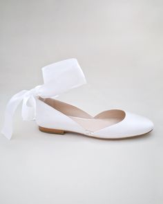 a pair of white shoes with a bow on the front