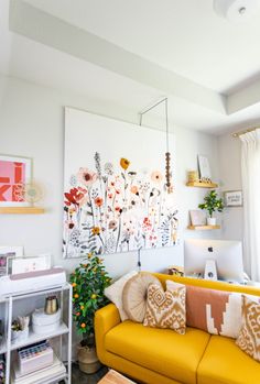 a living room with yellow couches and pictures on the wall above them, along with other decor items