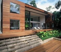 a modern house with wood sidings and glass doors on the outside, surrounded by greenery