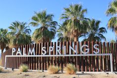 palm trees are in front of a sign that says palm springs on the side of a fence