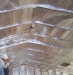 two men are working on the roof of a building with tin foil covering it and one man is wearing a white hard hat