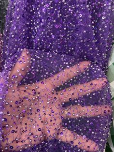 a person's hand is covered in purple sequins