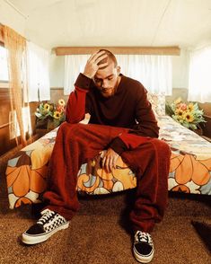 a man sitting on top of a bed in a room with sunflower bedspread