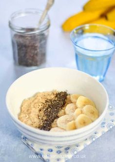 a bowl filled with oatmeal and bananas next to a glass of water