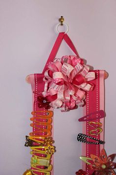 a pink door hanger decorated with colorful hair clips and a bow on the front