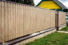 a wooden fence next to a house with a yellow building in the backround