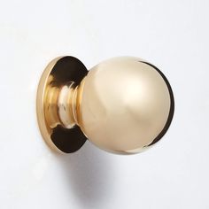 a golden door knob on a white wall with a black and gold ball at the top