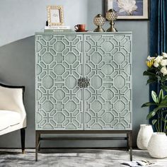 an ornate cabinet in the corner of a room with blue curtains and flowers on it