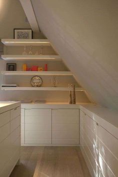 an attic kitchen with built in shelving and white cabinetry, along with wooden flooring