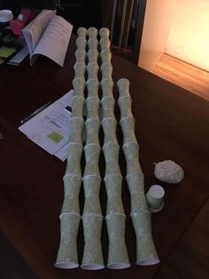 a bunch of candles sitting on top of a wooden table next to papers and cups