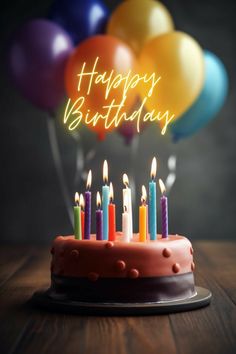 a birthday cake with lit candles on it and balloons in the background that say happy birthday