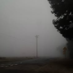 a foggy street with power lines and telephone poles