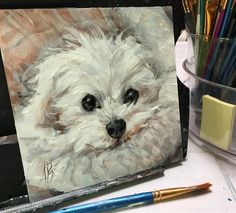 a painting of a white dog on a table next to paintbrushes and pens