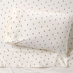 a bed with white sheets and black trees on the pillowcase, next to a pair of pillows