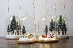 three snow globes with christmas trees in them and lights strung from the top one