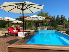 an outdoor pool with lounge chairs and umbrellas