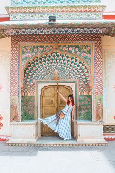 a woman in a blue and white dress is standing on the steps outside an ornate building