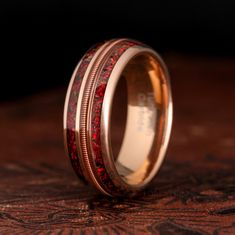 a wedding ring with red and gold inlays on the inside, sitting on top of a wooden table