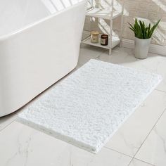 a white bath mat sitting on top of a bathroom floor