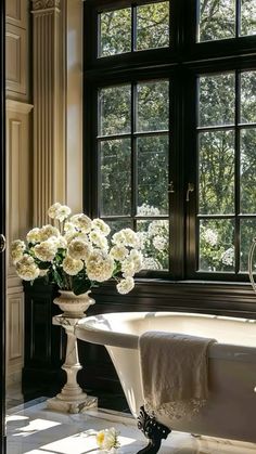 a bath tub sitting next to a window filled with white flowers