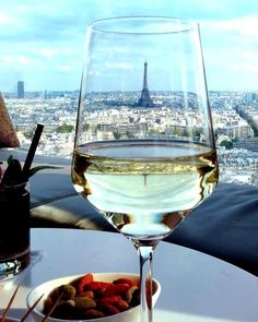 a glass of white wine with a view of the eiffel tower